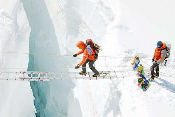 Samy, character in the film, The Clmb, crossing an ice crevice with a horizontal ladder